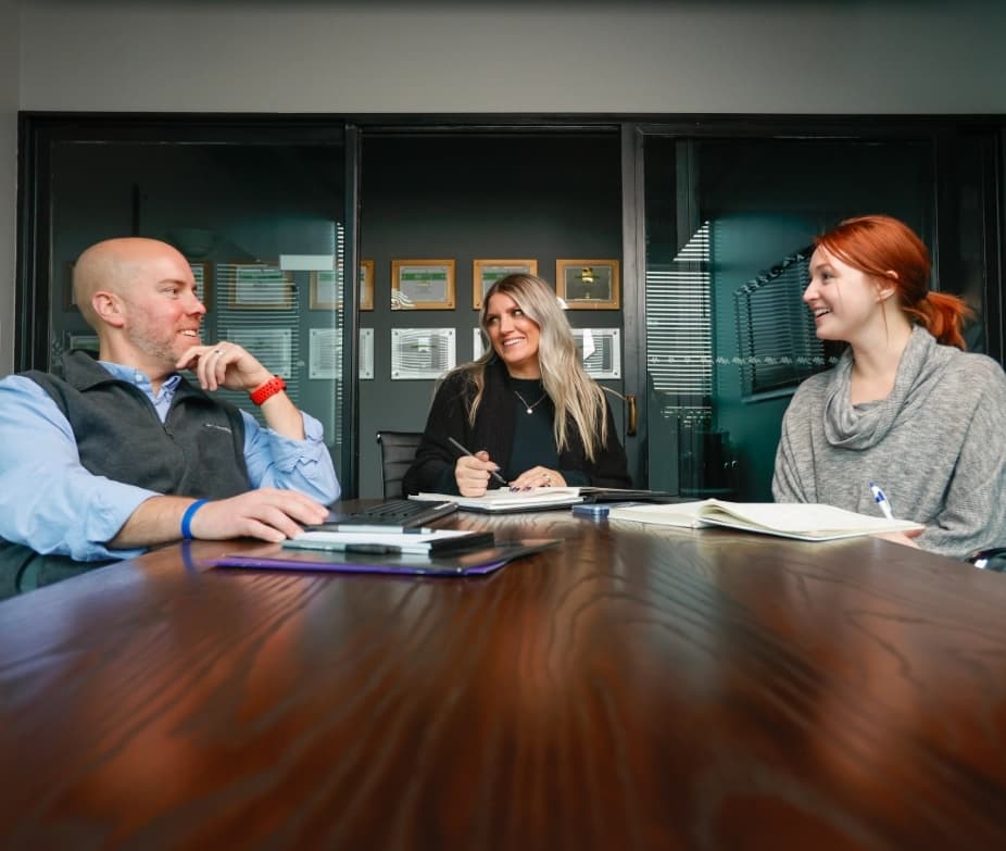 Banner image of 3 happy people talking around a table