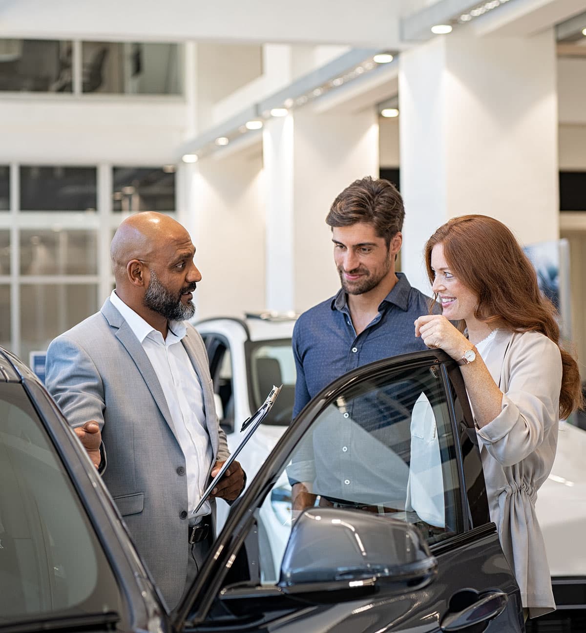 Couple examining new auto with car dealer