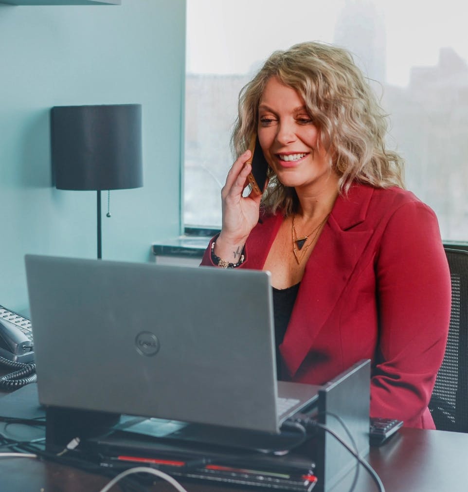 Banner image of woman on her laptop while on the phone smiling