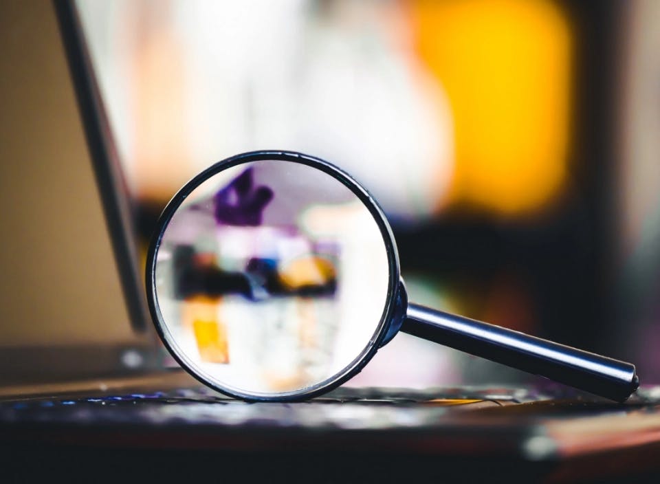 Banner image of a magnifying glass next to a laptop