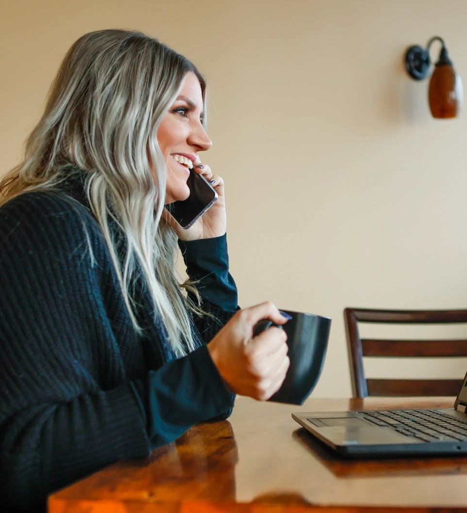 Banner image of woman on the phone smiling with a cup of coffee in her hand